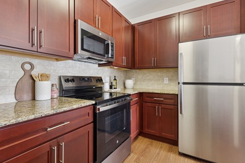 A kitchen with brown cabinets and a stainless steel refrigerator.