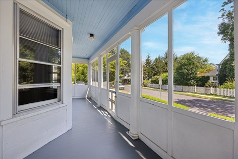 A long white porch with a blue ceiling and white railings.