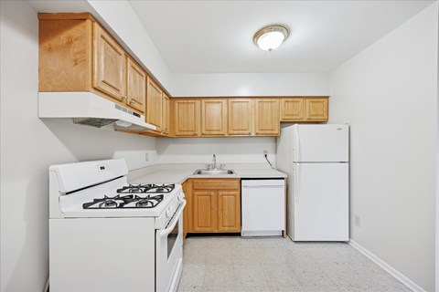 A kitchen with white appliances and wooden cabinets.