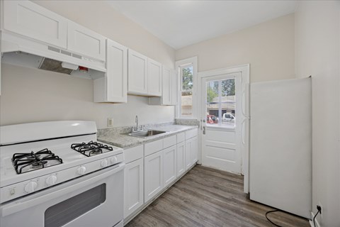 A kitchen with white cabinets and a white stove top oven.