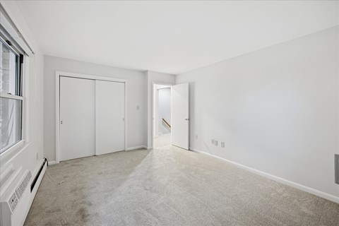A spacious room with white walls and carpeted floor.
