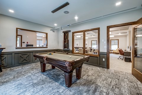 A room with a pool table and a mirror.
