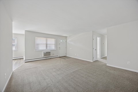 A spacious living room with a fireplace and carpeted floor.