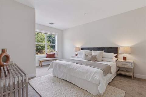 A bedroom with a large bed and a window seat.