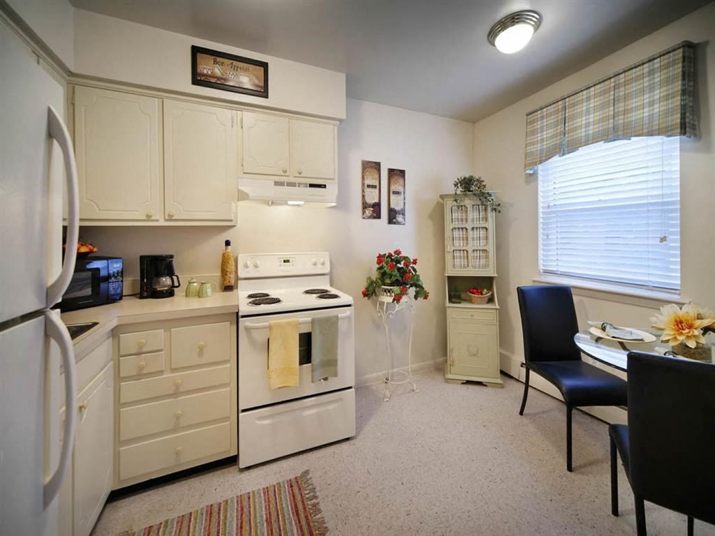 a kitchen with white appliances and a table and chairs