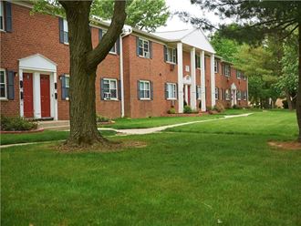 a row of brick apartment buildings with green grass and trees