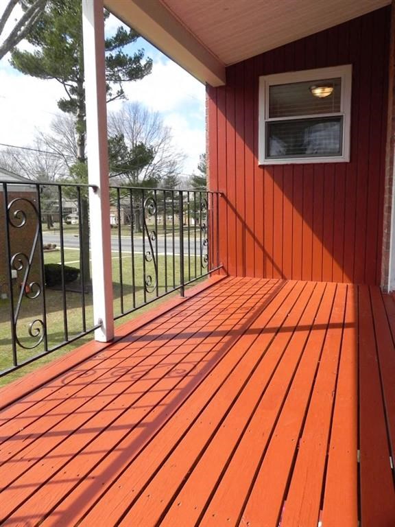 a porch with a wooden floor and a red house