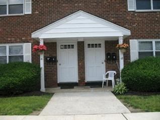 a red brick house with two white doors and a sidewalk