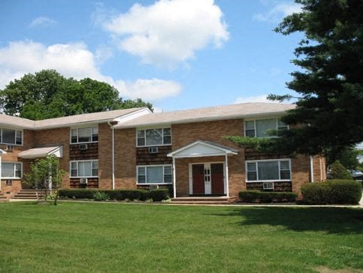 a large brick apartment building with a green lawn