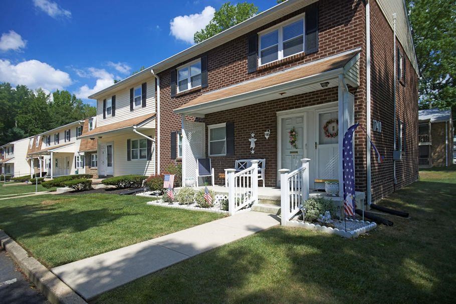 a brick house with a porch and a white fence