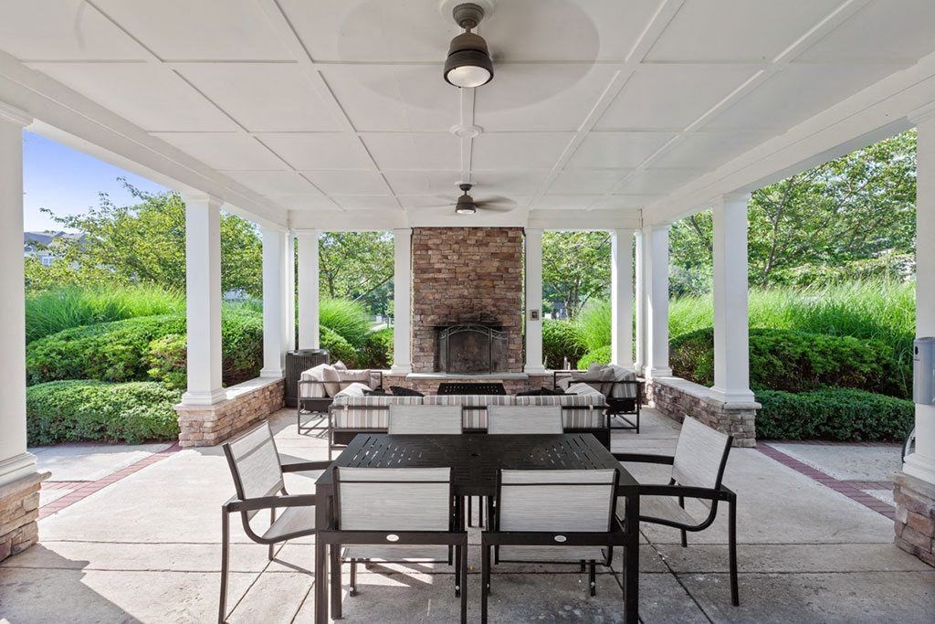 a covered patio with a fireplace and a dining table and chairs  at Harper's Crossing, Langhorne, PA, 19047