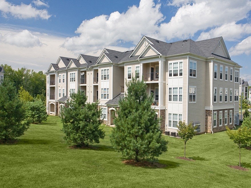 a large apartment building on a sunny day with trees in front of it  at Harper's Crossing, Pennsylvania