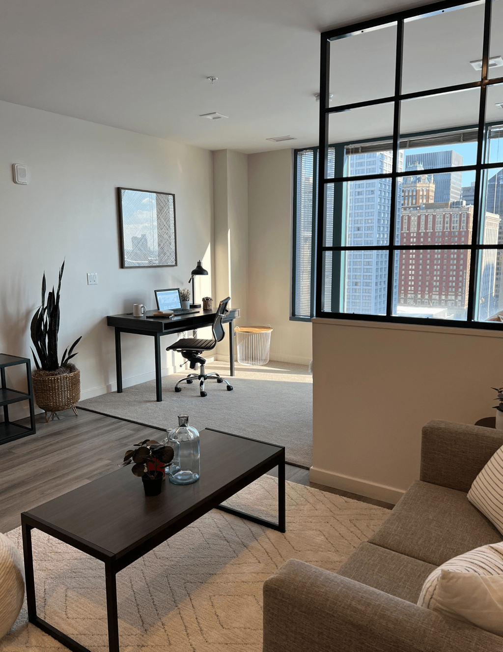 the living room of an apartment with a desk and a couch