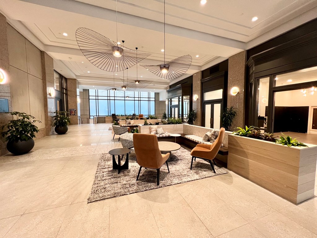 a large lobby with chairs and tables and a reception desk