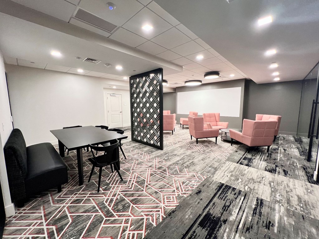 a room with chairs and tables and a projector screen