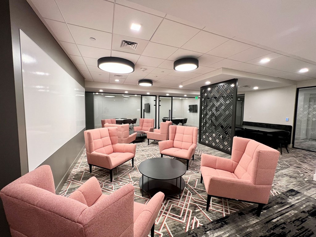 a waiting room with pink chairs and a black and white rug
