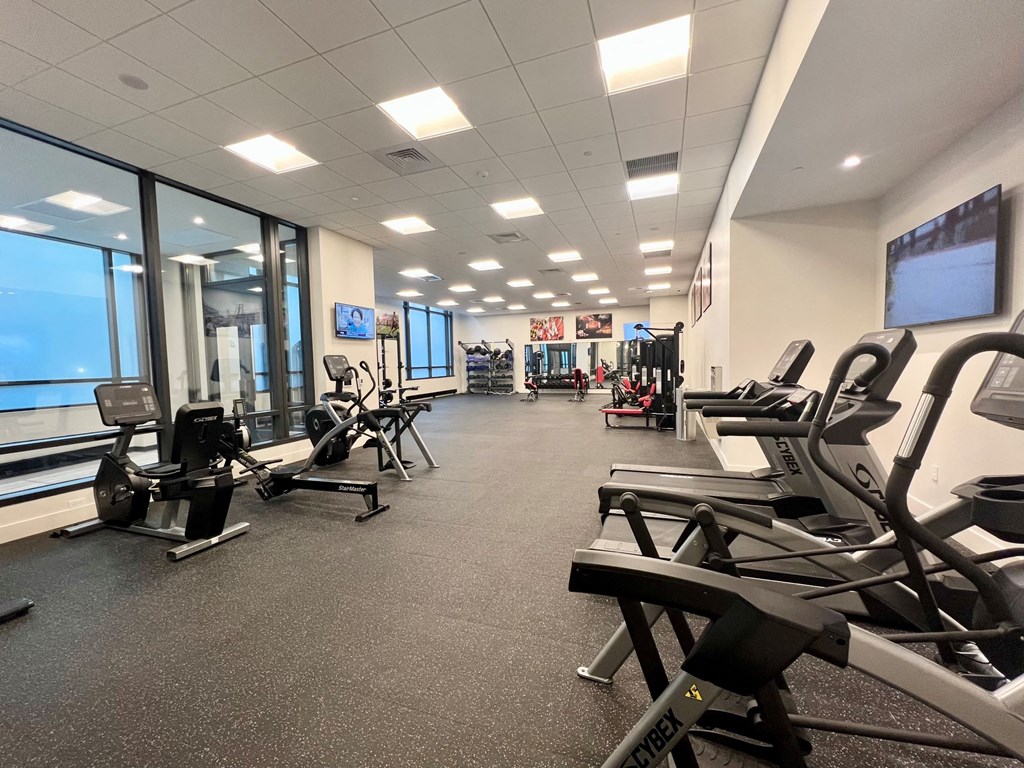 a gym with cardio equipment and windows in a building