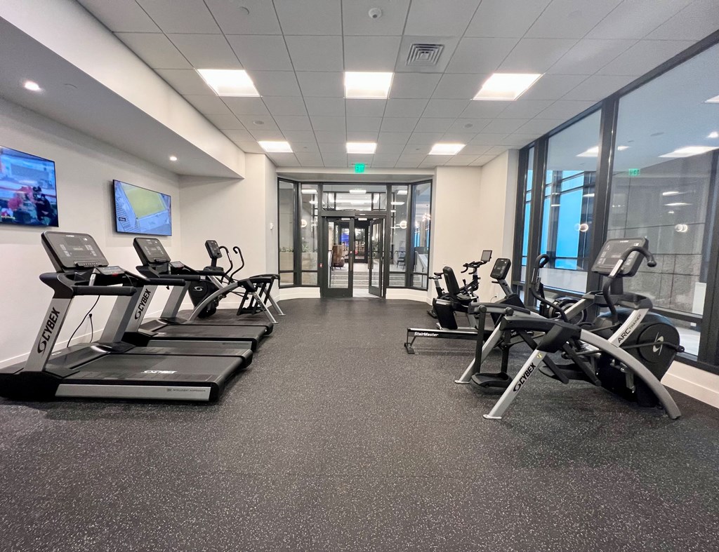 a gym with cardio equipment and windows in a building