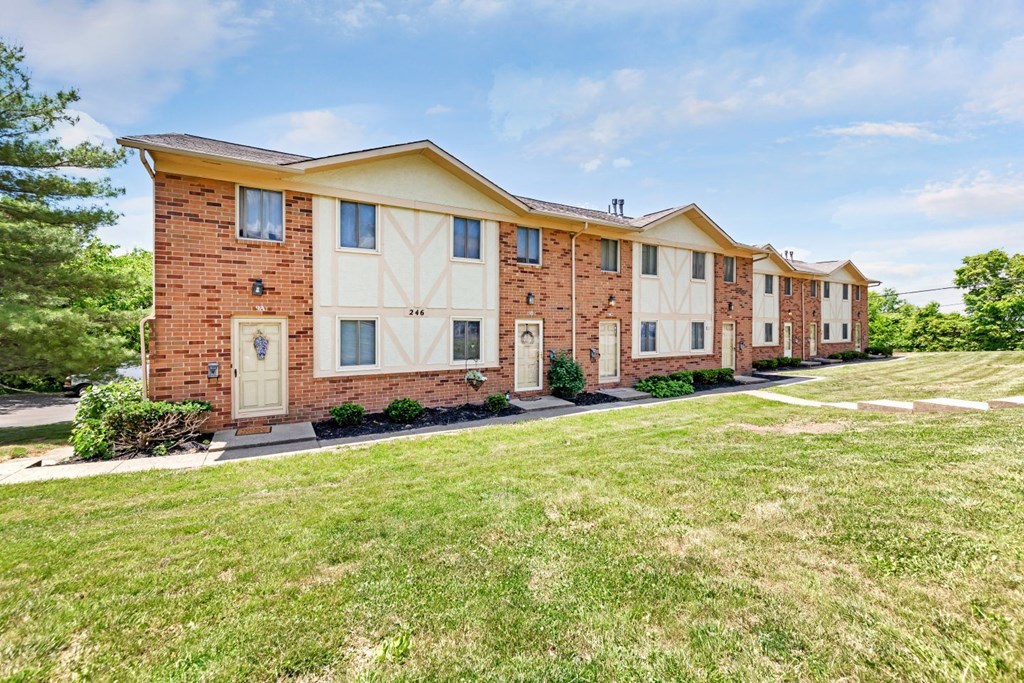 a brick apartment building with a lawn in front of it