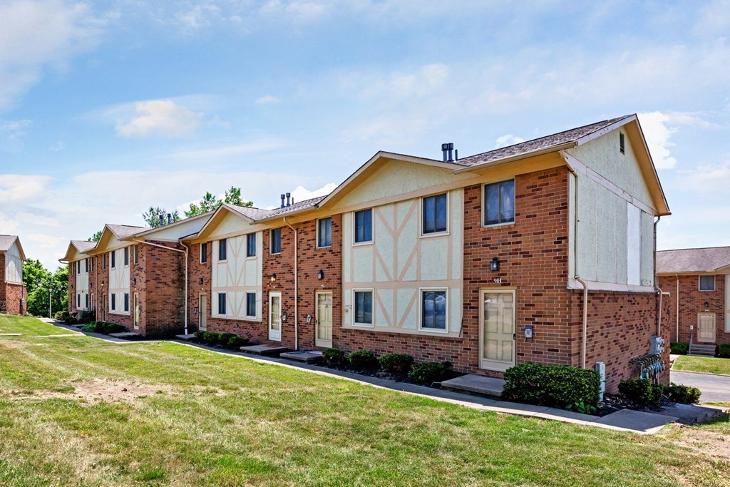 a row of brick apartment buildings with grass in front