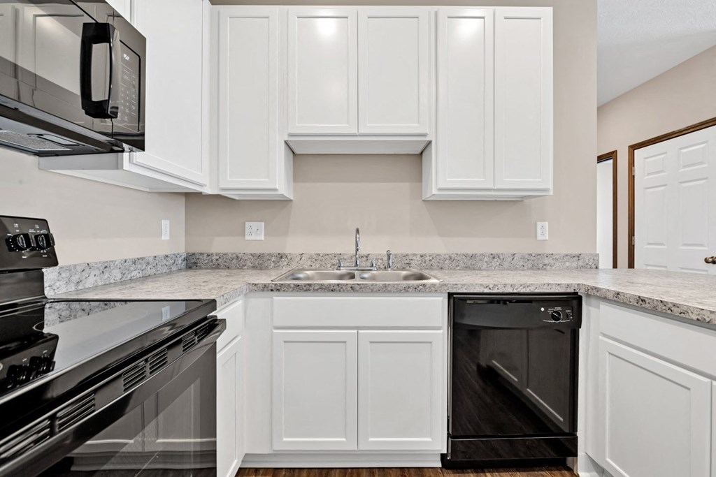 an empty kitchen with white cabinets and black appliances