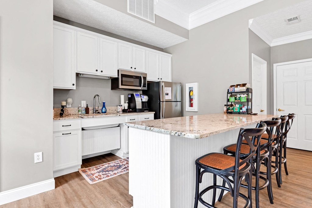 a kitchen with white cabinets and a counter with bar stools