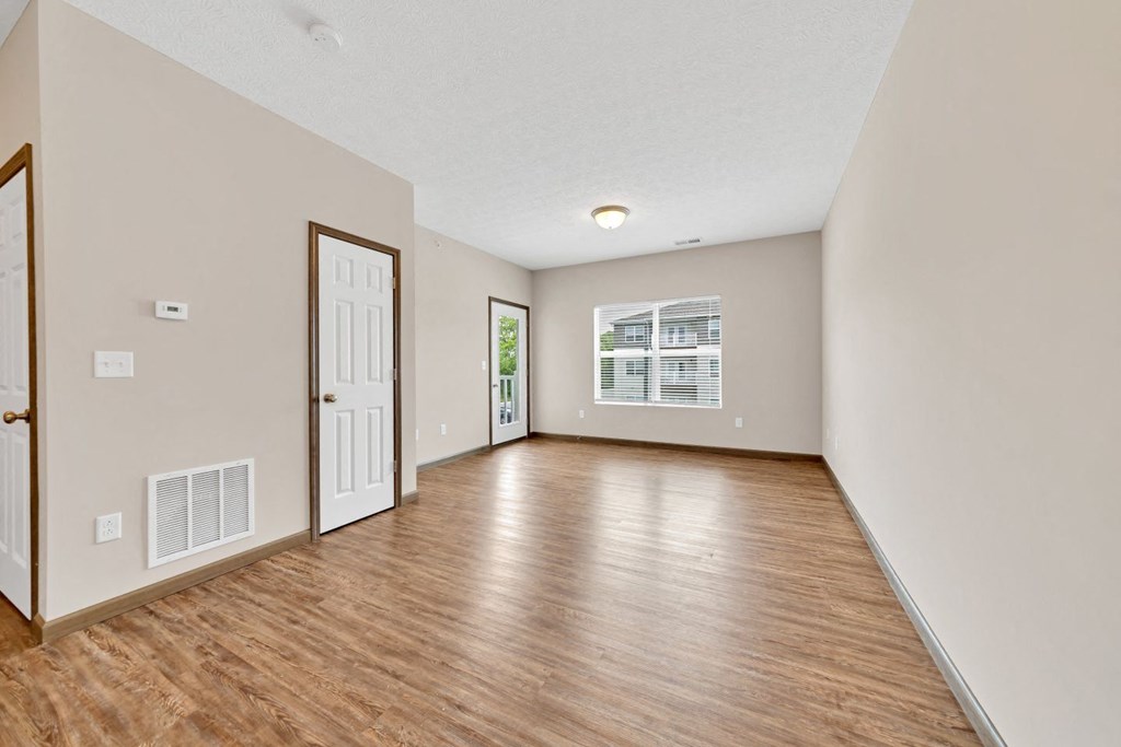 the living room and dining room of an empty house with wood flooring