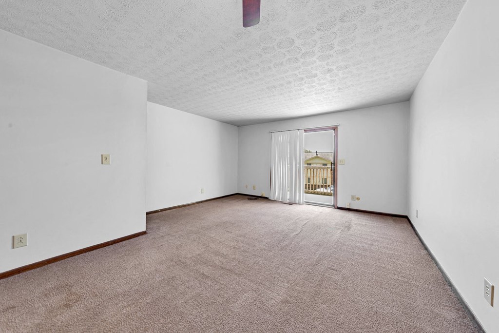 an empty living room with a door to a balcony