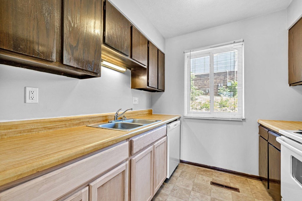 a kitchen with wooden cabinets and a sink and a window