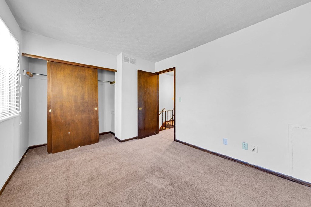a living room with carpet and a door to a hallway