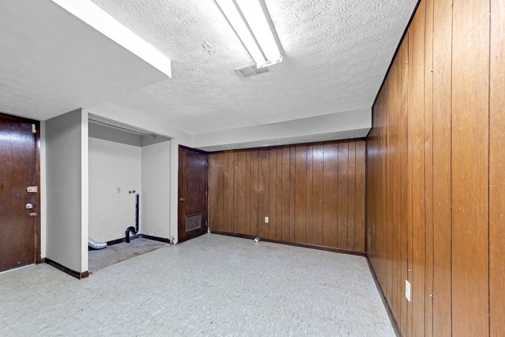 an empty room with wood paneling and a white carpet
