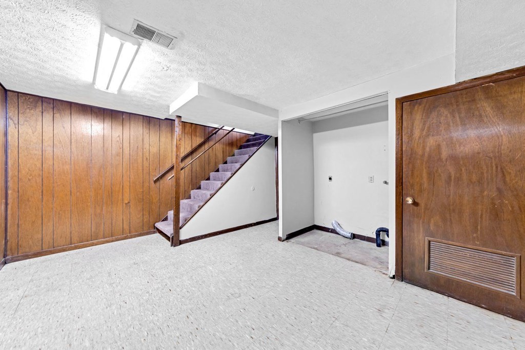 an empty living room with a wooden door and a staircase