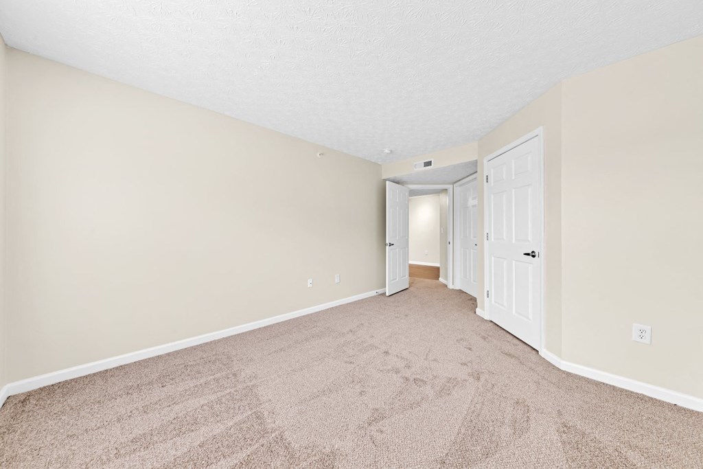 a spacious living room with carpet and a door to a hallway