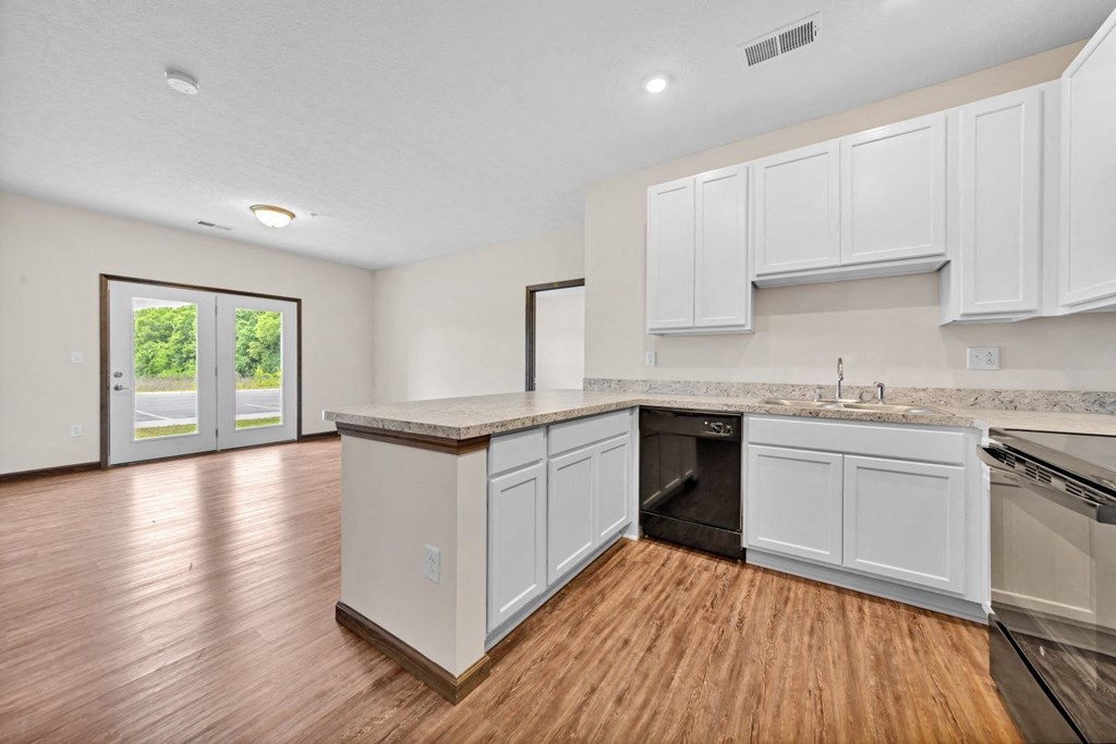 an empty kitchen with white cabinets and a wood floor
