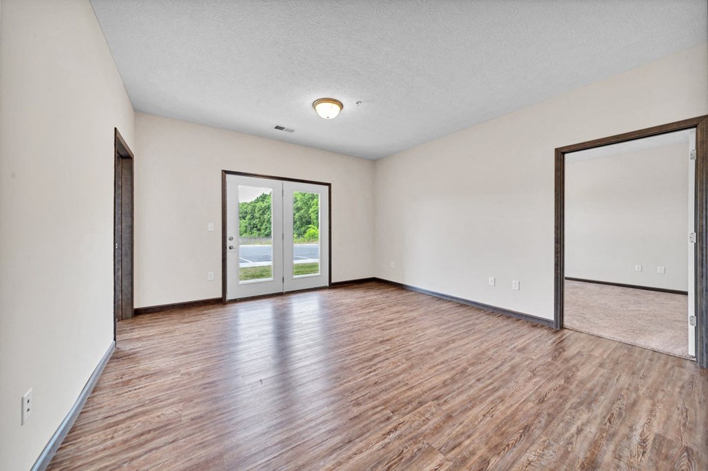 an empty living room with wood flooring and sliding glass doors