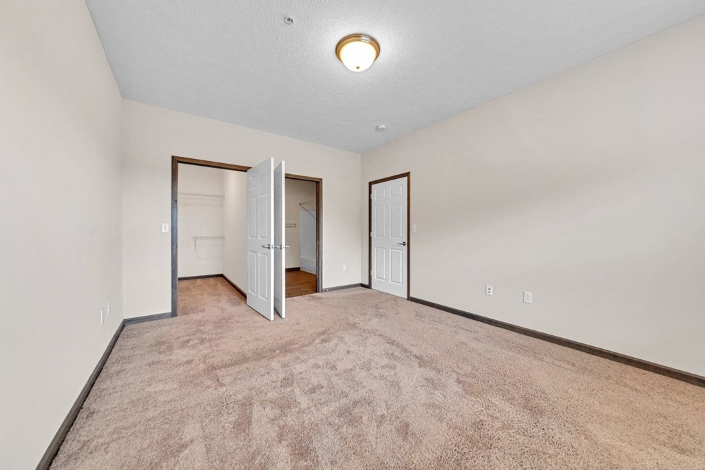 an empty living room with white walls and a door to a closet