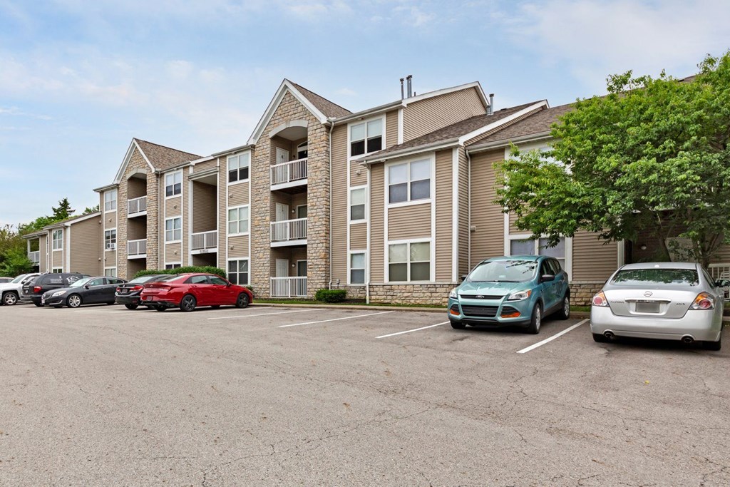 a parking lot with cars parked in front of an apartment building