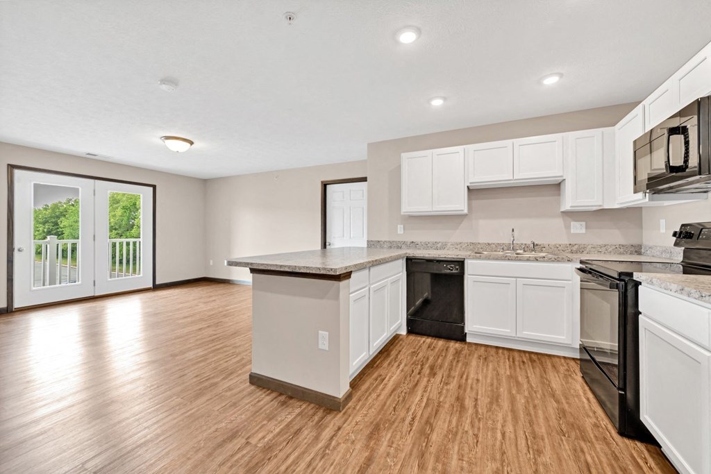 an open kitchen and living room with a door to a balcony