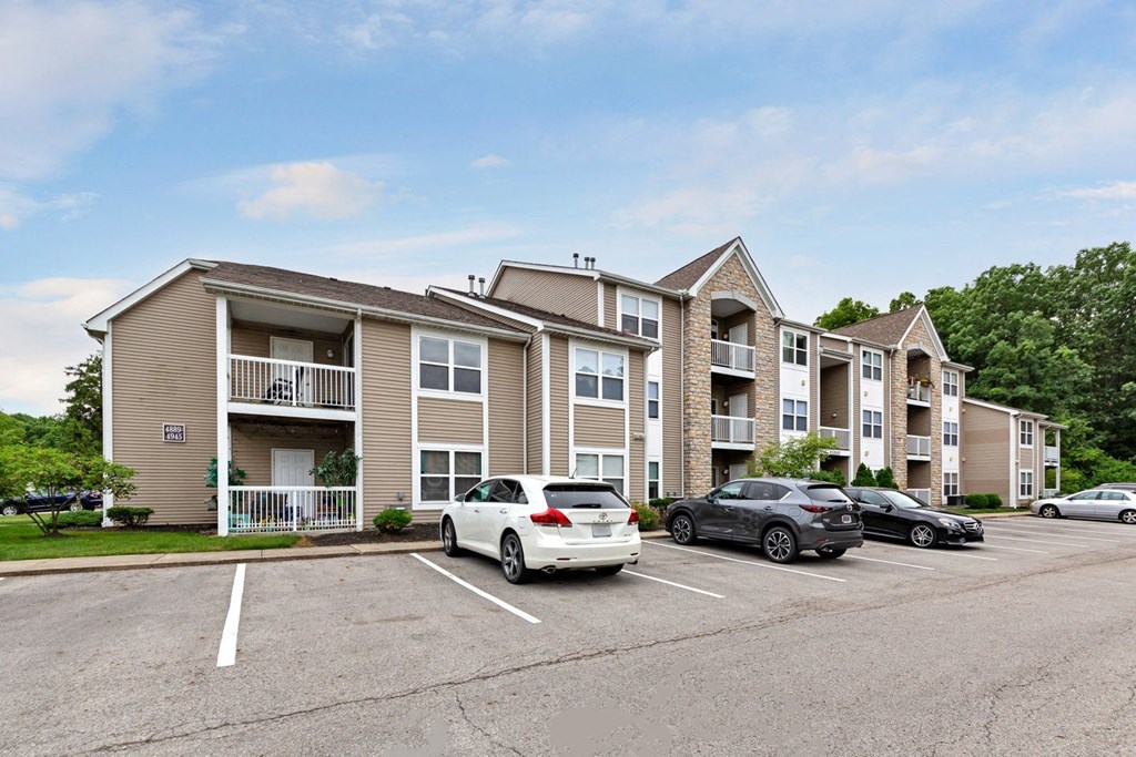 a parking lot with cars in front of an apartment building