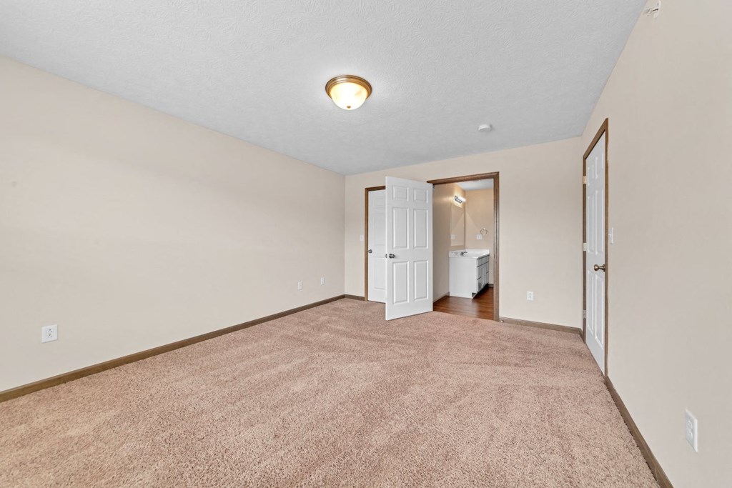 a spacious living room with carpet and a door to a bathroom