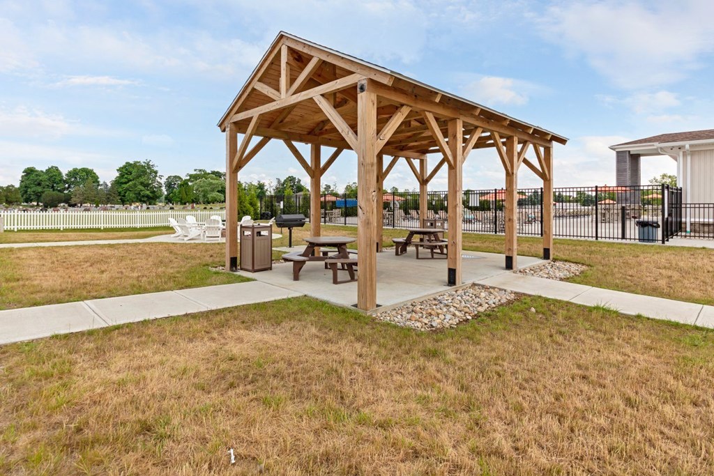 a picnic pavilion in a park with benches and picnic tables