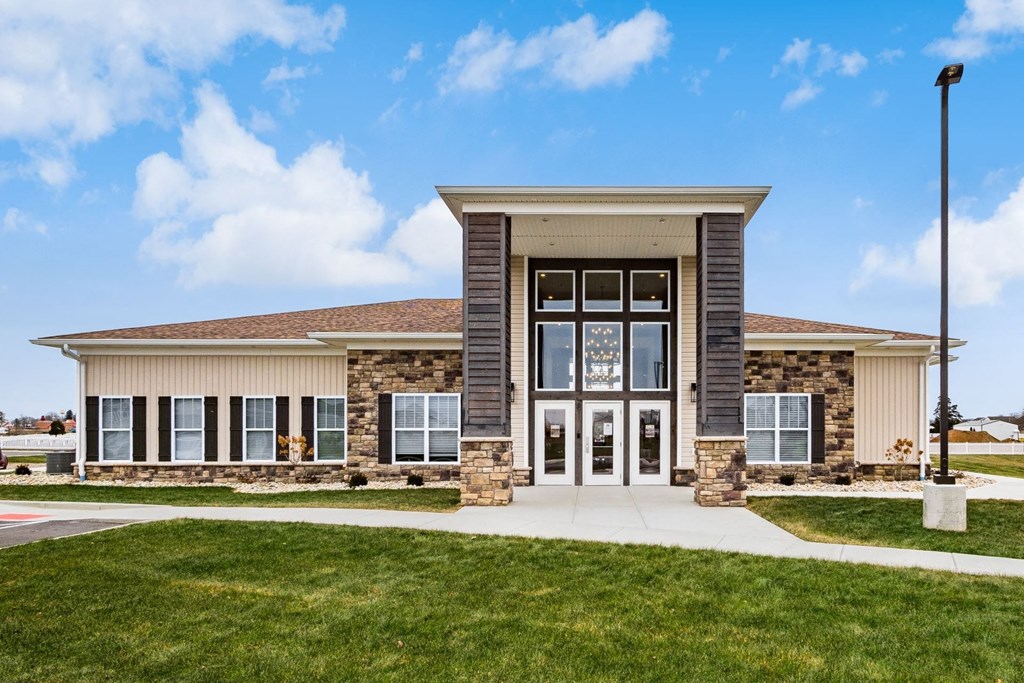 the front of a building with glass doors and a lawn