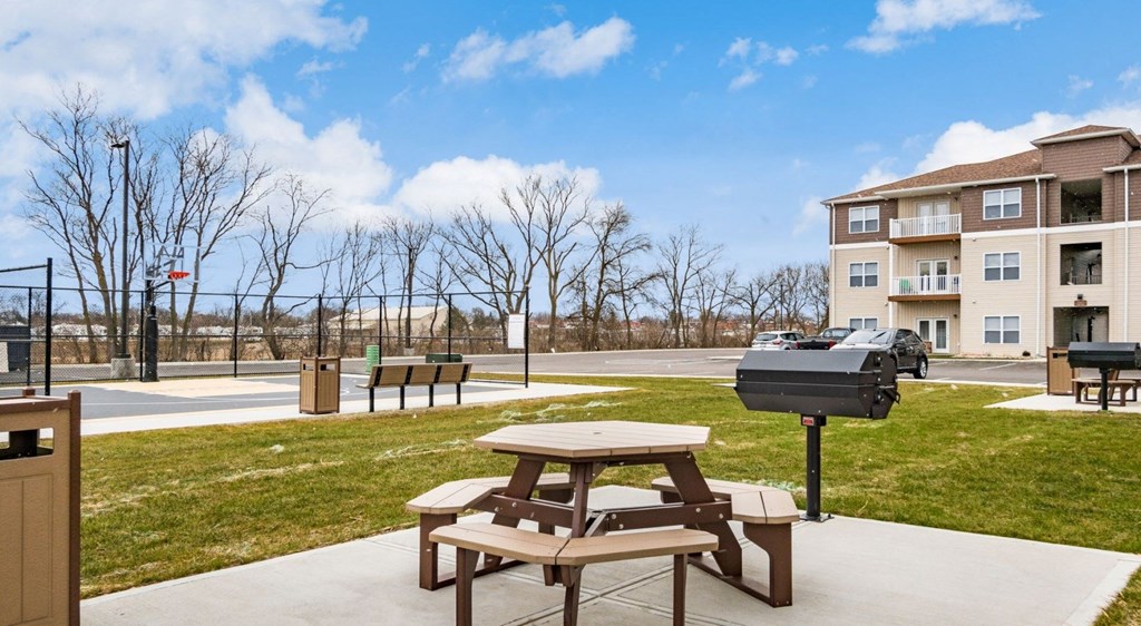 a picnic table with a grill in front of an apartment building