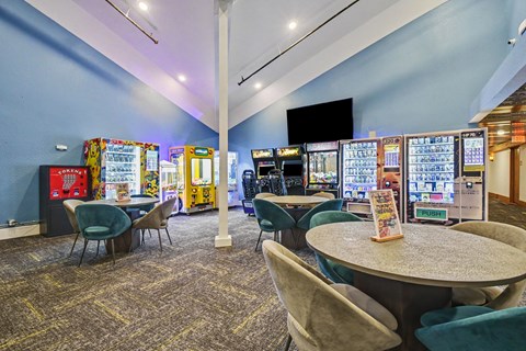 A room with a table surrounded by chairs and a wall of arcade games.