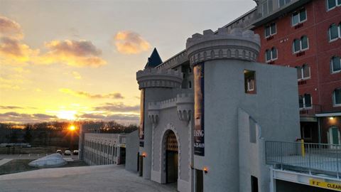 the sun sets behind a building with a castle entrance