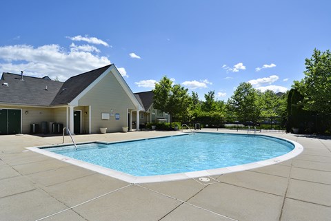 A small building is behind a pool.