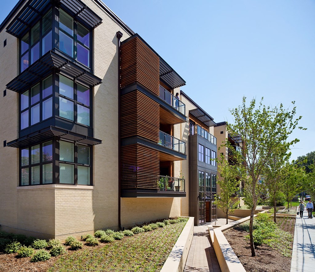 a row of modern buildings with a sidewalk and trees