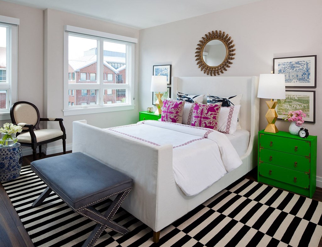 a bedroom with a white bed and a black and white striped rug