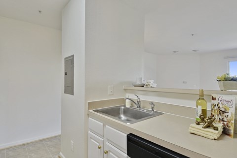 A kitchen with a sink and a counter with a bottle of wine on it.