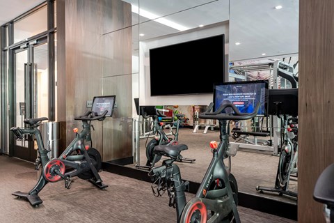 A gym with stationary bikes and a TV screen.